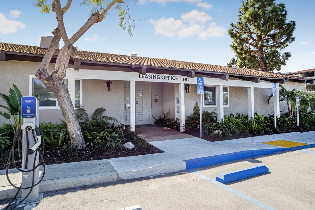 A leasing office is located in front of a building with a parking lot in front.