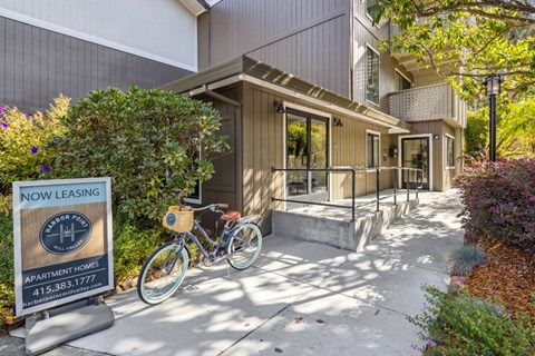 Apartment leasing sign with a bicycle in front of a building.