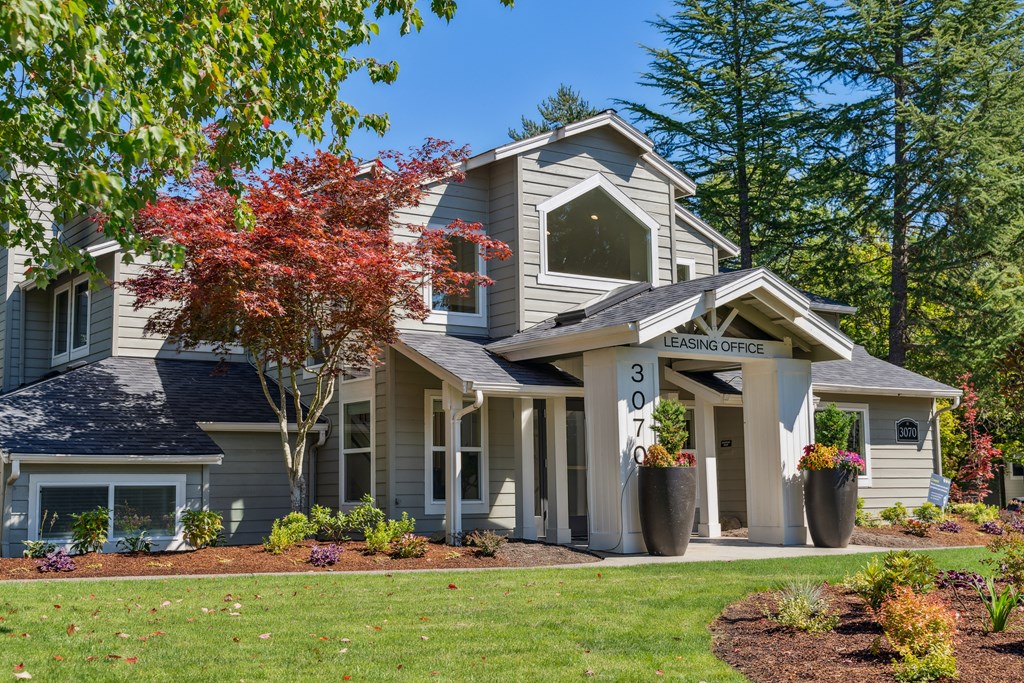 the front of a house with a lawn and trees