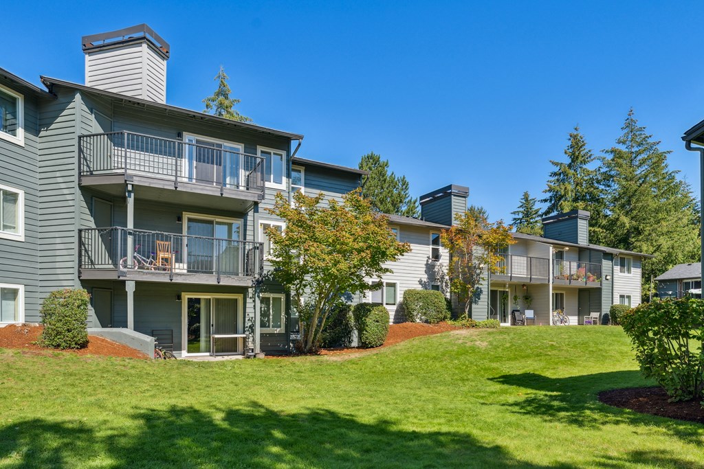 a view of an apartment building with green grass and trees