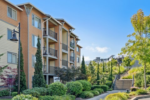 an exterior view of an apartment building with trees and a sidewalk
