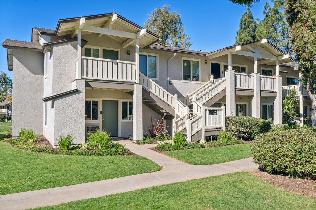 a house with stairs and a sidewalk in front of a yard