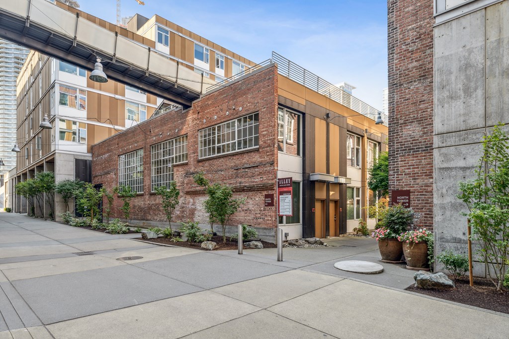 the exterior of a brick building with a bridge over the sidewalk