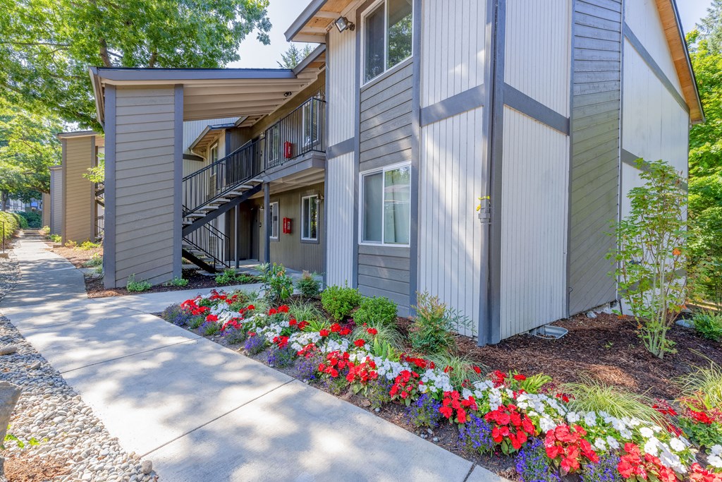 a house with a sidewalk and flowers in front of it