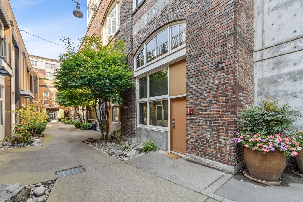 the front door of a brick apartment building with flowers on the sidewalk
