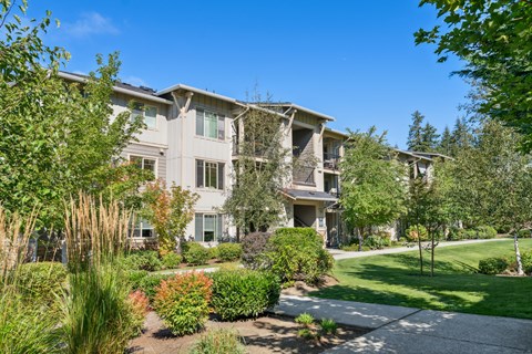 an apartment building with a lawn and trees in front of it