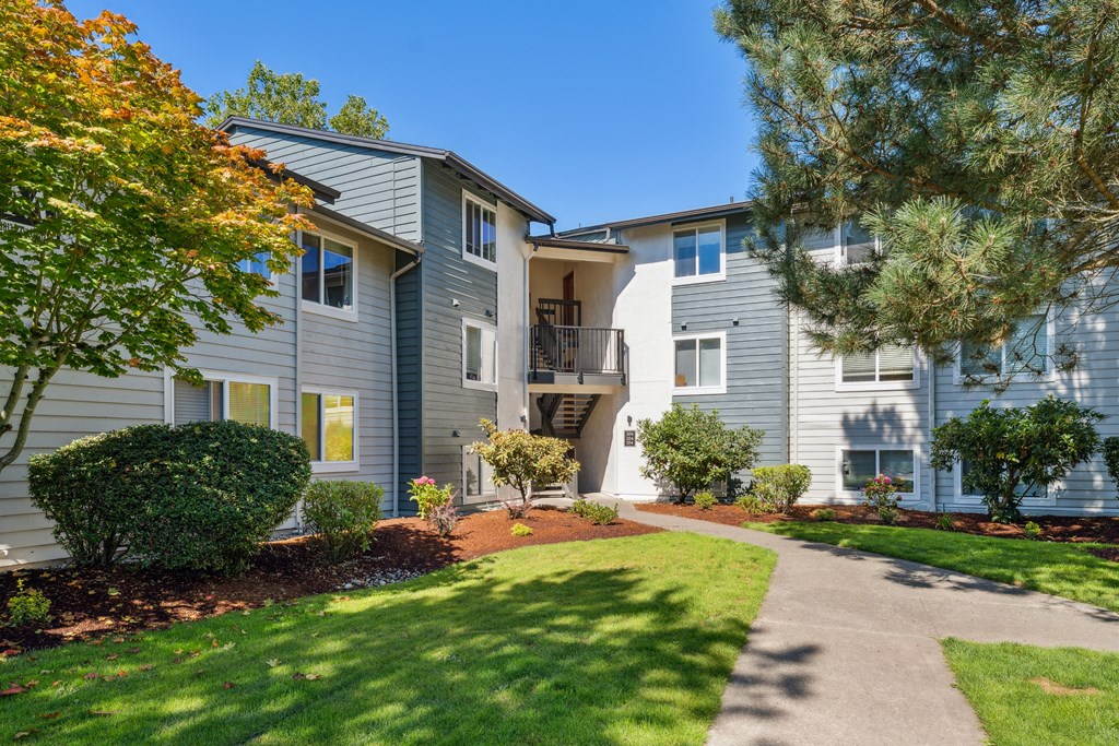 a walkway between two apartment buildings with grass and trees