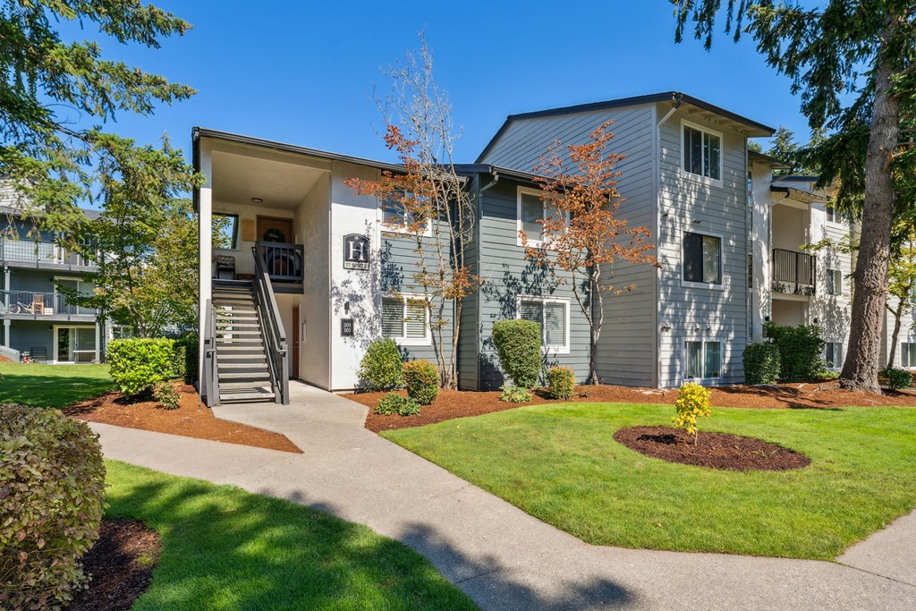 a gray building with stairs and a sidewalk in front of it