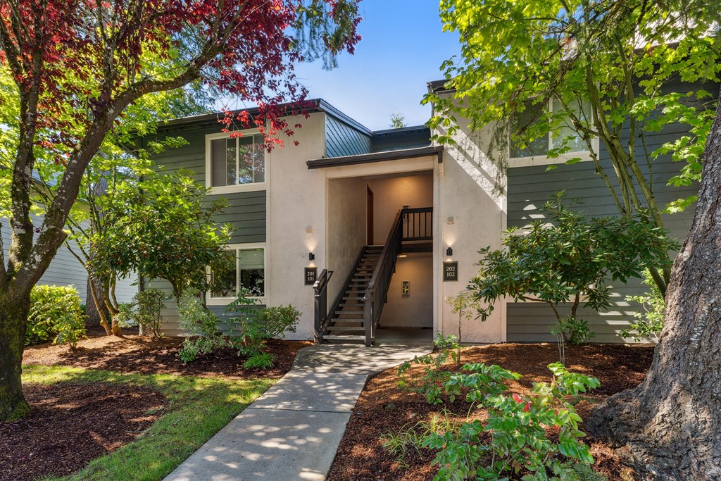 the front of a house with trees and a sidewalk