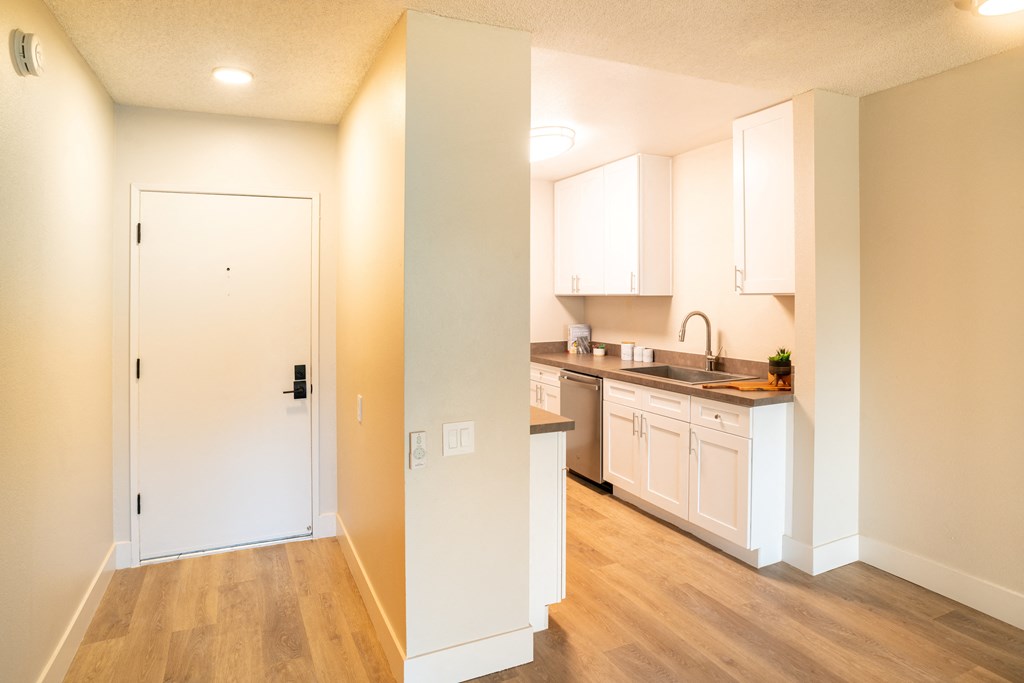 a view of a kitchen with white cabinets and a door
