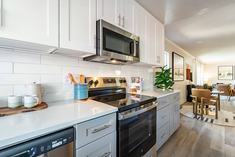 A modern kitchen with a black stove top oven and white cabinets.