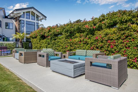 A row of grey wicker chairs and tables are set up on a patio.