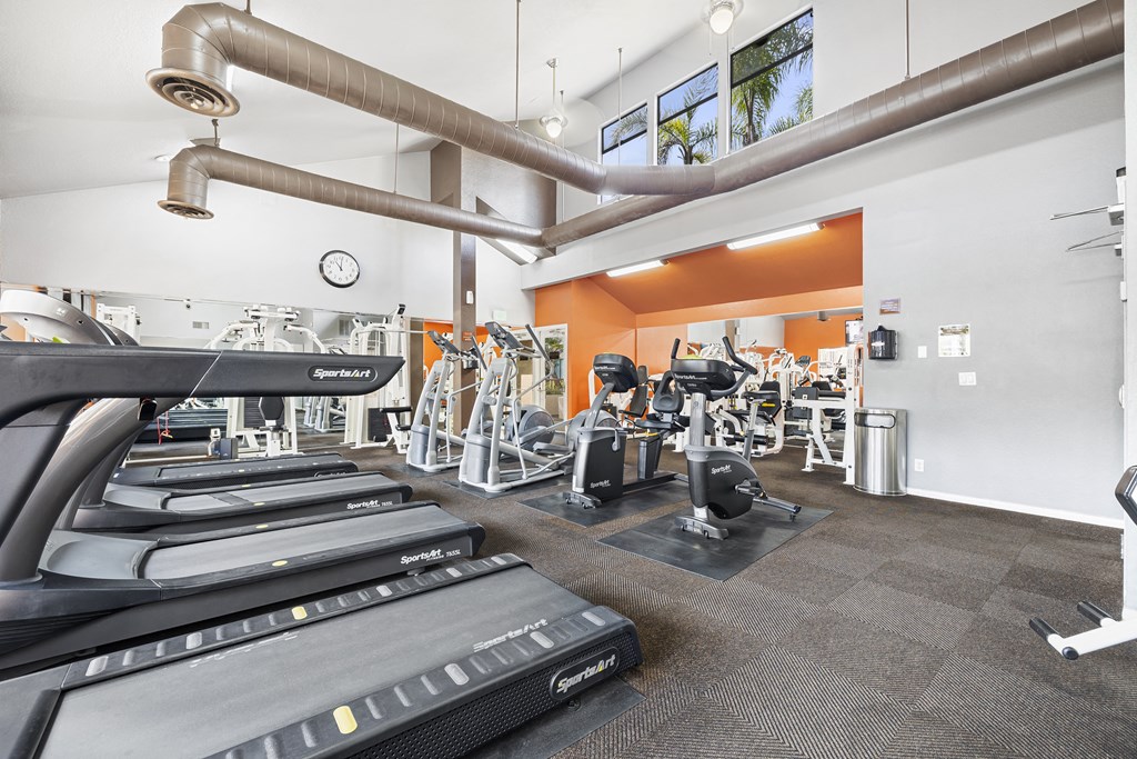 a gym with treadmills and other exercise equipment in a building with orange walls