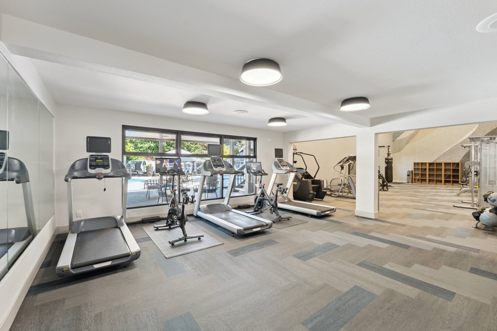 a gym with treadmills and other exercise equipment in a building with windows