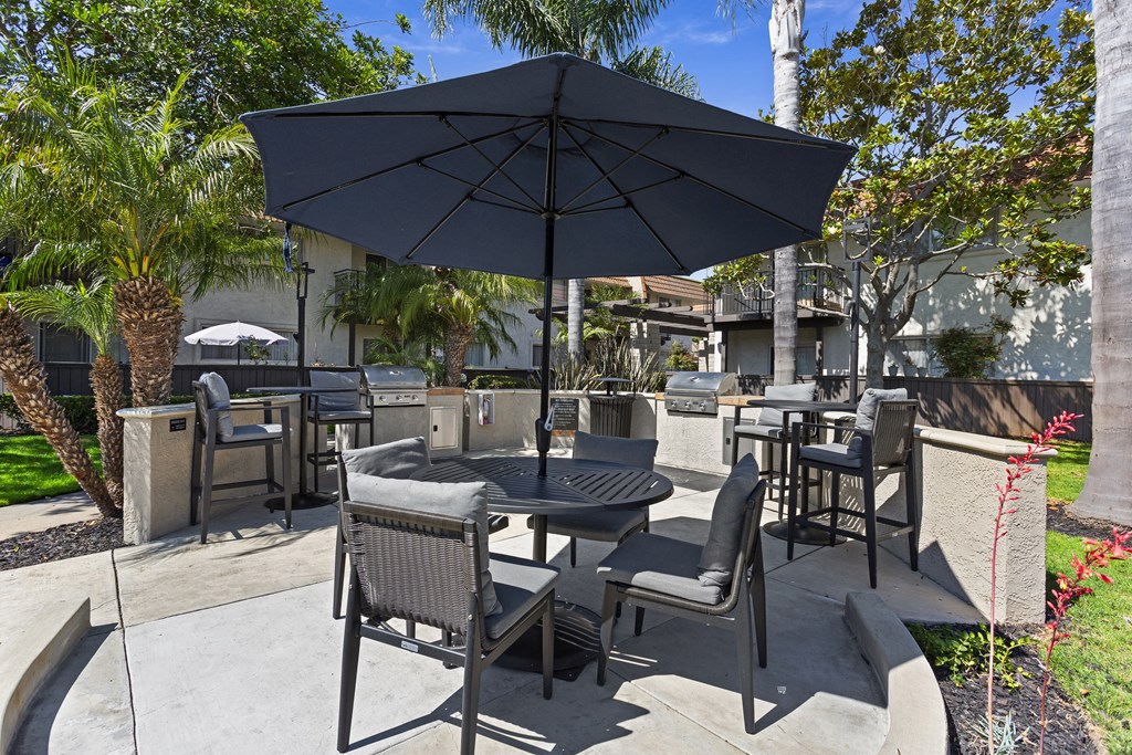 a patio with tables and chairs and an umbrella