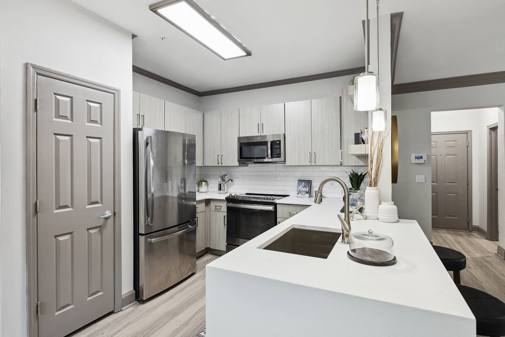 a white kitchen with stainless steel appliances and white counter tops