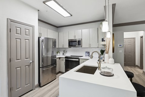 a white kitchen with stainless steel appliances and white counter tops