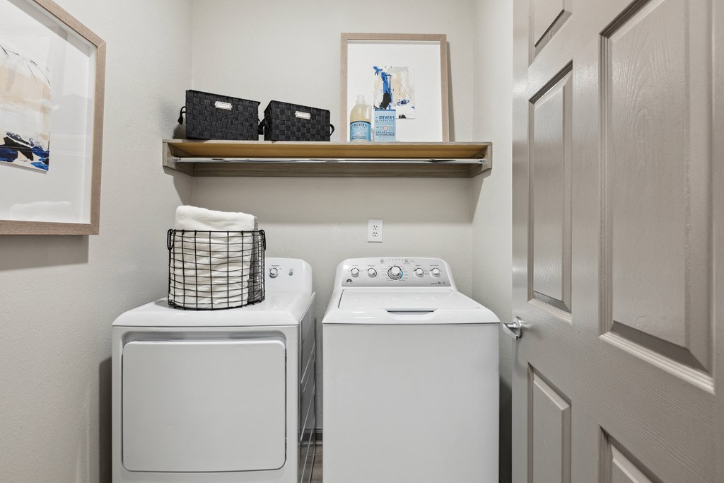 a white washer and dryer in a small laundry room with a shelf above