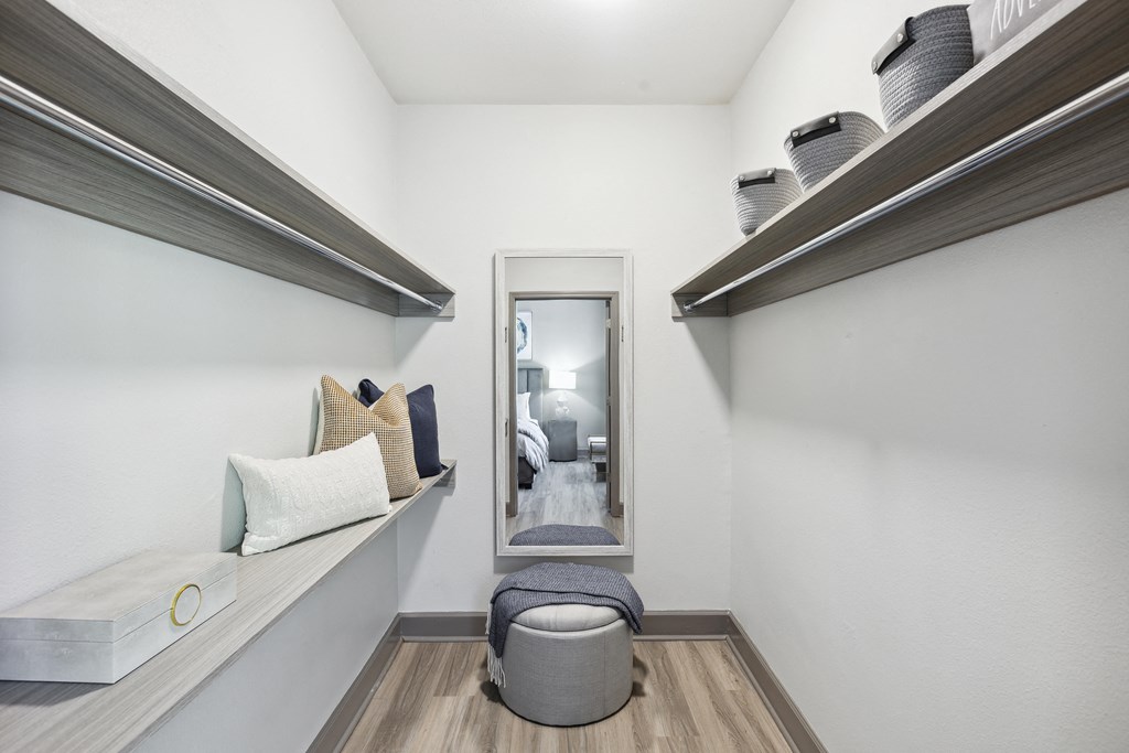 a hallway with shelves and a mirror and a seating area with pillows