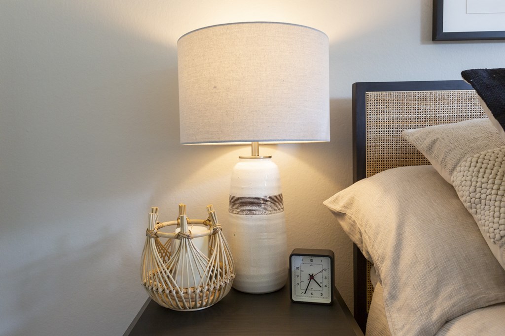 a nightstand with a lamp and a clock on it