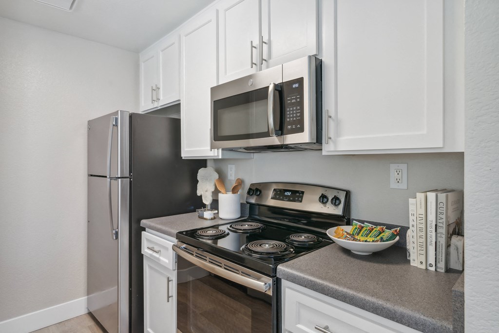 a kitchen with white cabinets and stainless steel appliances and a refrigerator