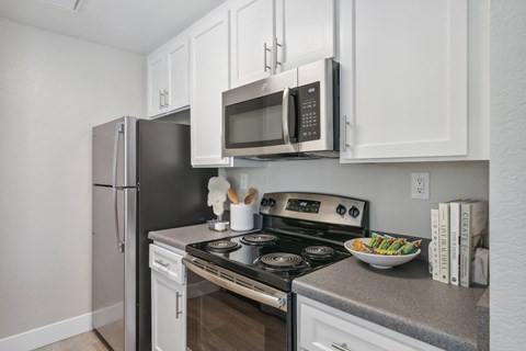 a kitchen with white cabinets and stainless steel appliances and a refrigerator