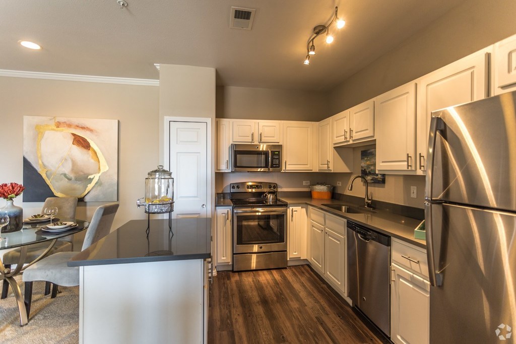A modern kitchen with stainless steel appliances and white cabinets. at The Viridian Apartments, Greenwood Village 80111