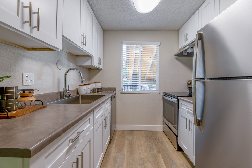 an empty kitchen with stainless steel appliances and white cabinets