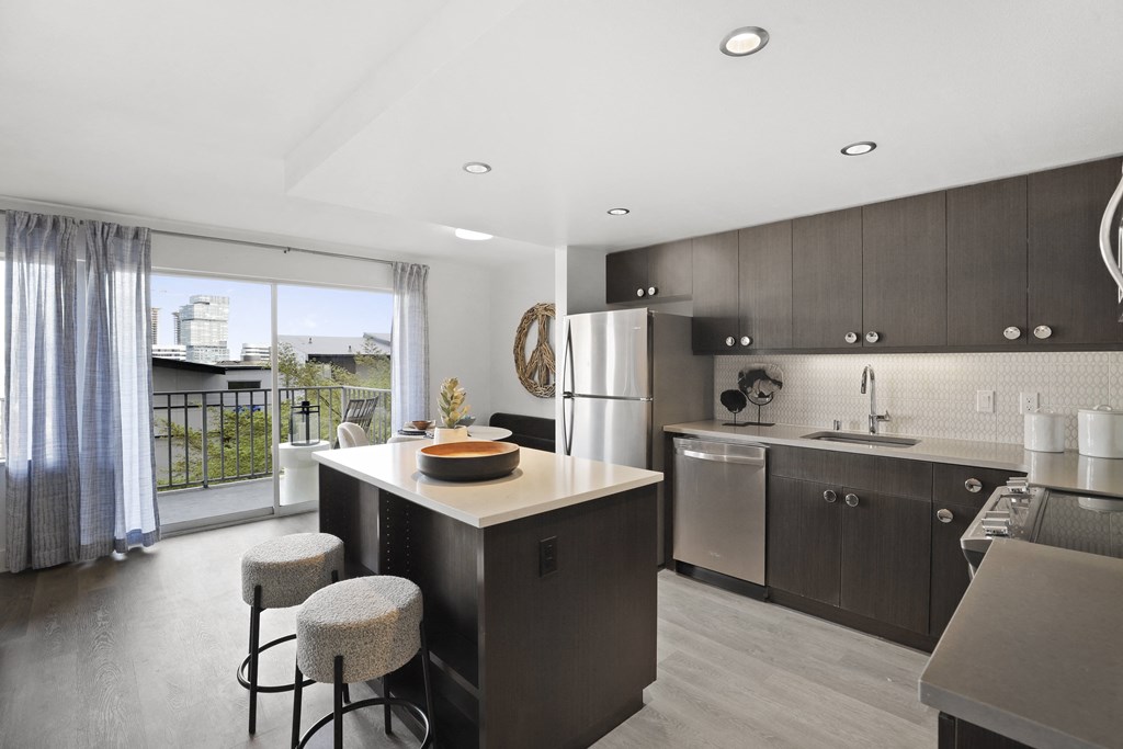 a kitchen with a large island and a stainless steel refrigerator