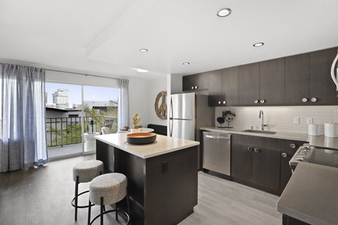 a kitchen with a large island and a stainless steel refrigerator