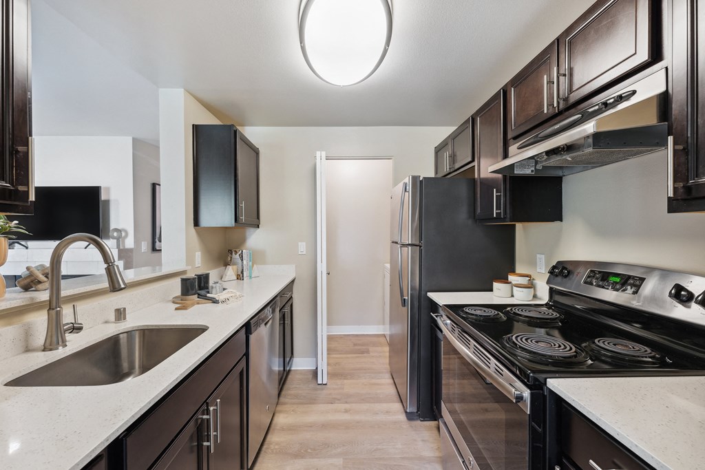 a kitchen with black appliances and white countertops and a stainless steel refrigerator