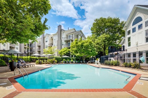 A swimming pool surrounded by trees and apartment buildings.