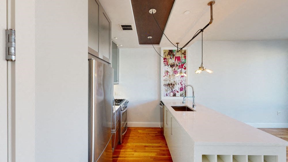 A modern kitchen with a white countertop and stainless steel appliances.