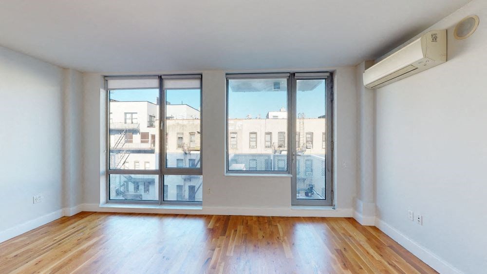 A room with wooden floors and a large window overlooking a city street.