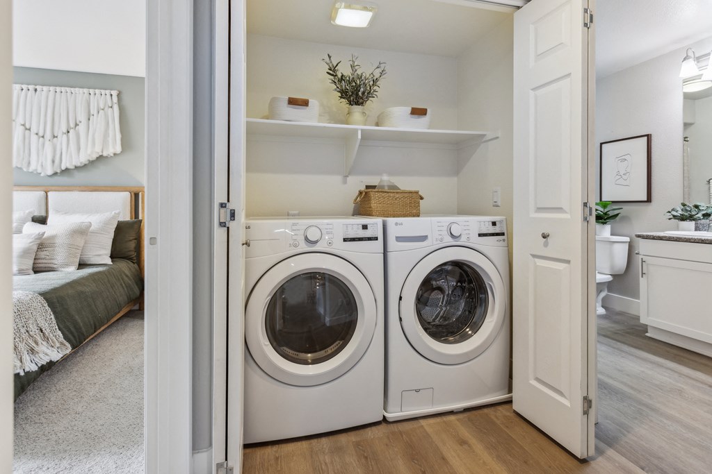 a white washer and dryer in a room with a bathroom and a bed