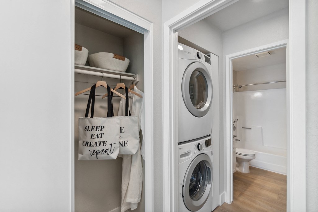 a small bathroom with a washer and dryer and a door to a laundry