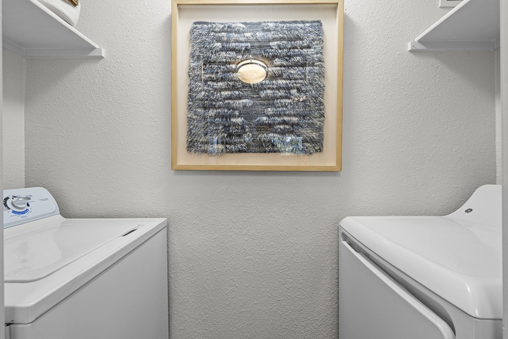 a small bathroom with a washer and dryer and a painting on the wall