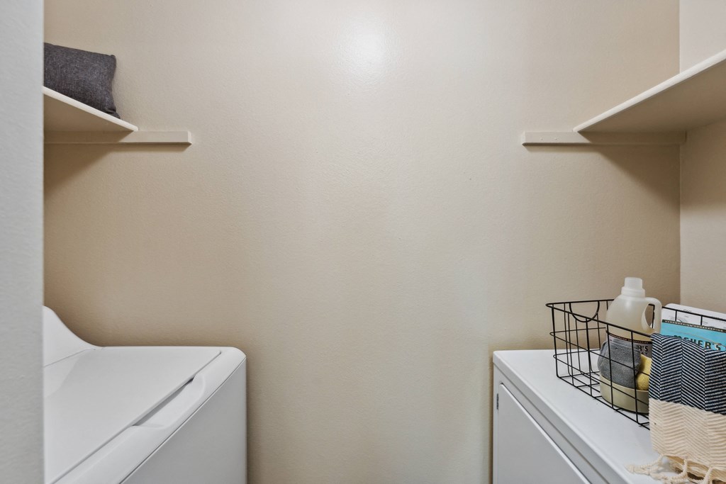a small laundry room with a washer and dryer and a shelf with towels