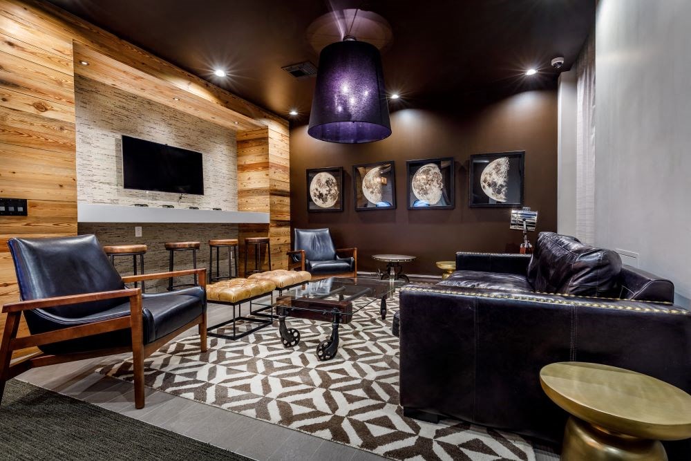 A modern living room with a wooden wall and a black couch.