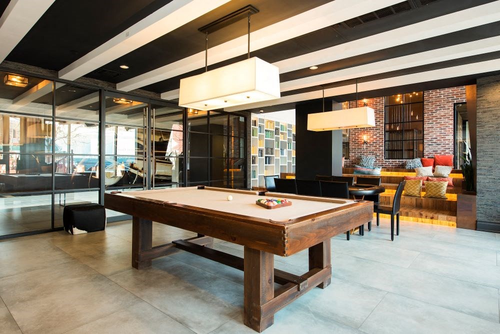 A pool table in a room with a glass wall.