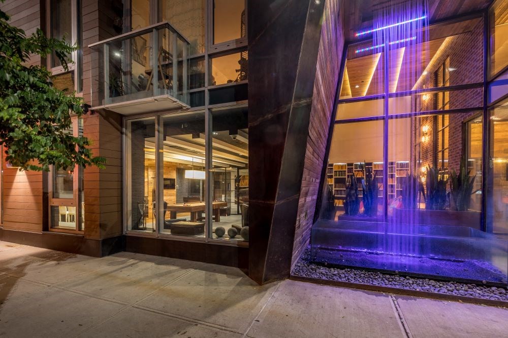 A modern building with a glass facade and a purple light on the right side.