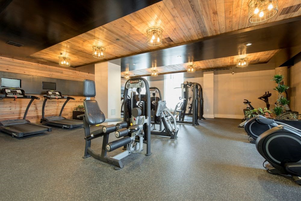 A gym with a variety of equipment including treadmills, weights, and exercise machines.