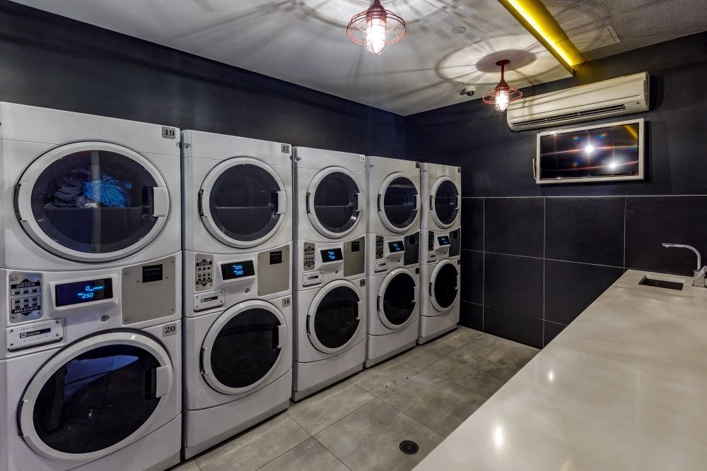 A row of front-loading washing machines in a laundromat.