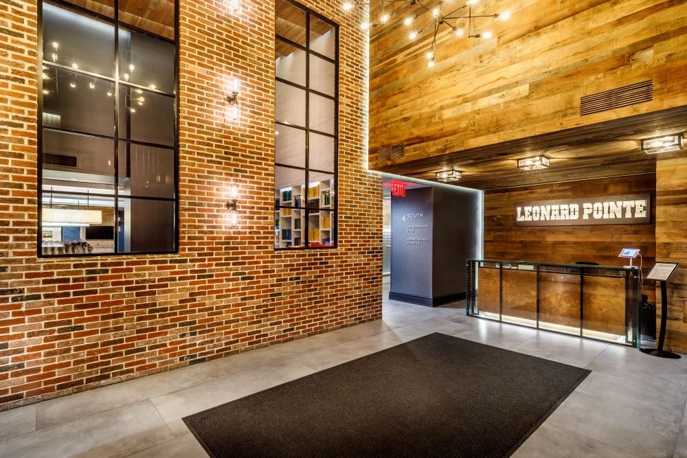 The image shows a reception area with a brick wall and a sign that reads "Leonard Pointe.".