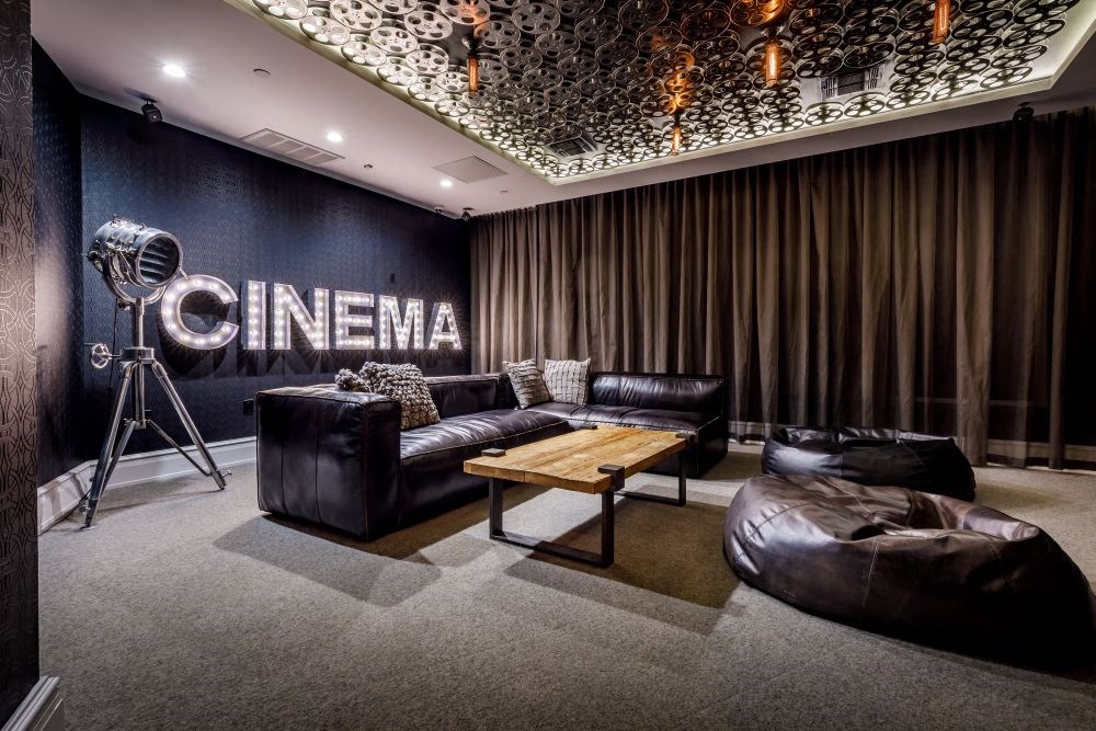 A modern cinema room with a large leather sofa and a wooden coffee table.