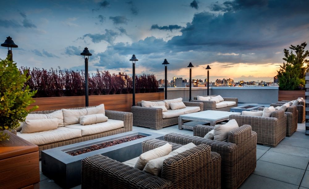 A patio with outdoor furniture and a view of the city skyline at dusk.