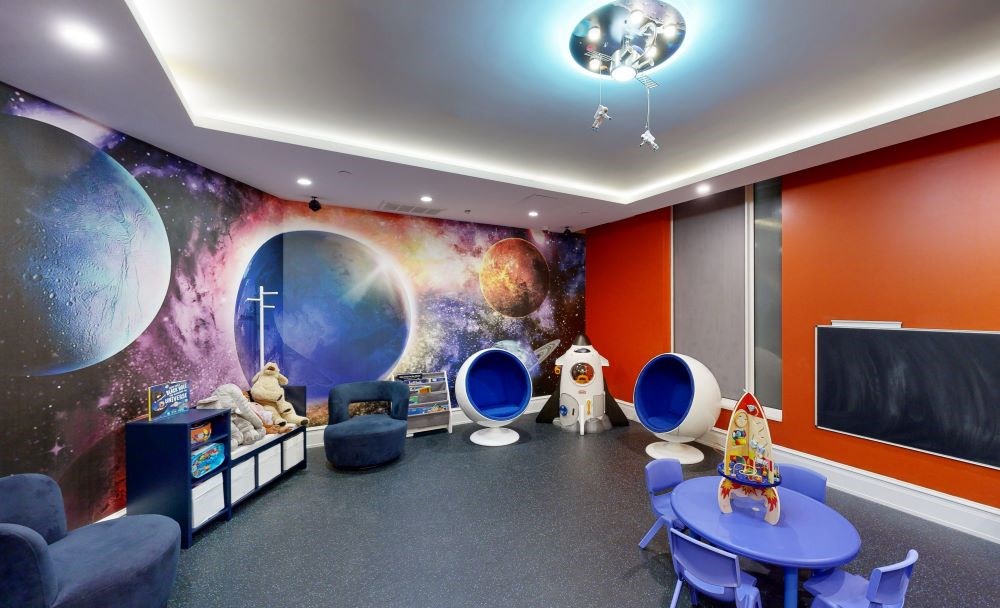 A room with a space theme, featuring a mural of planets and a blackboard.