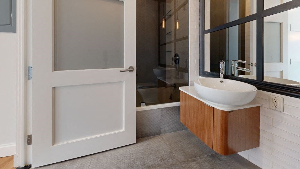 A white sink is on a wooden stand in a bathroom.