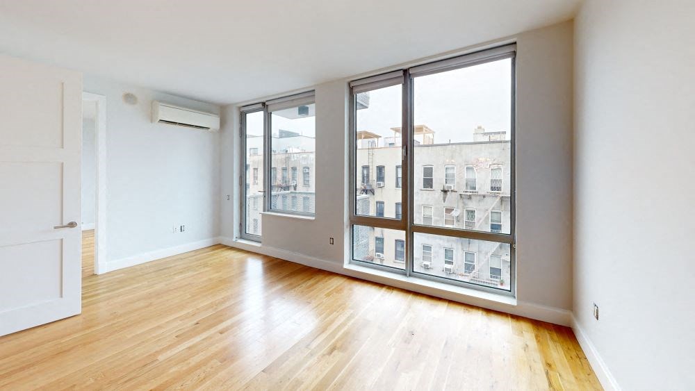 A room with wooden floors and a large window overlooking a building.