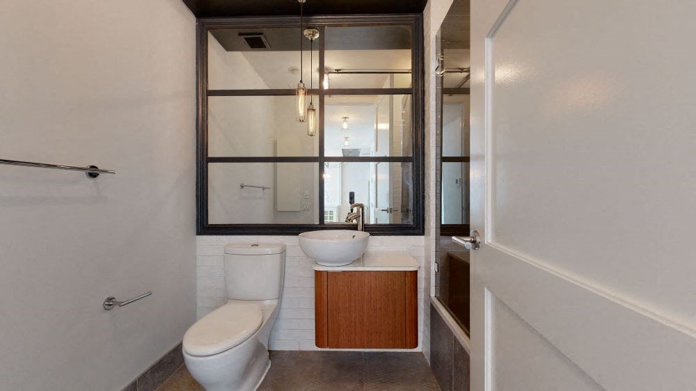 A white toilet sits next to a sink in a modern bathroom.